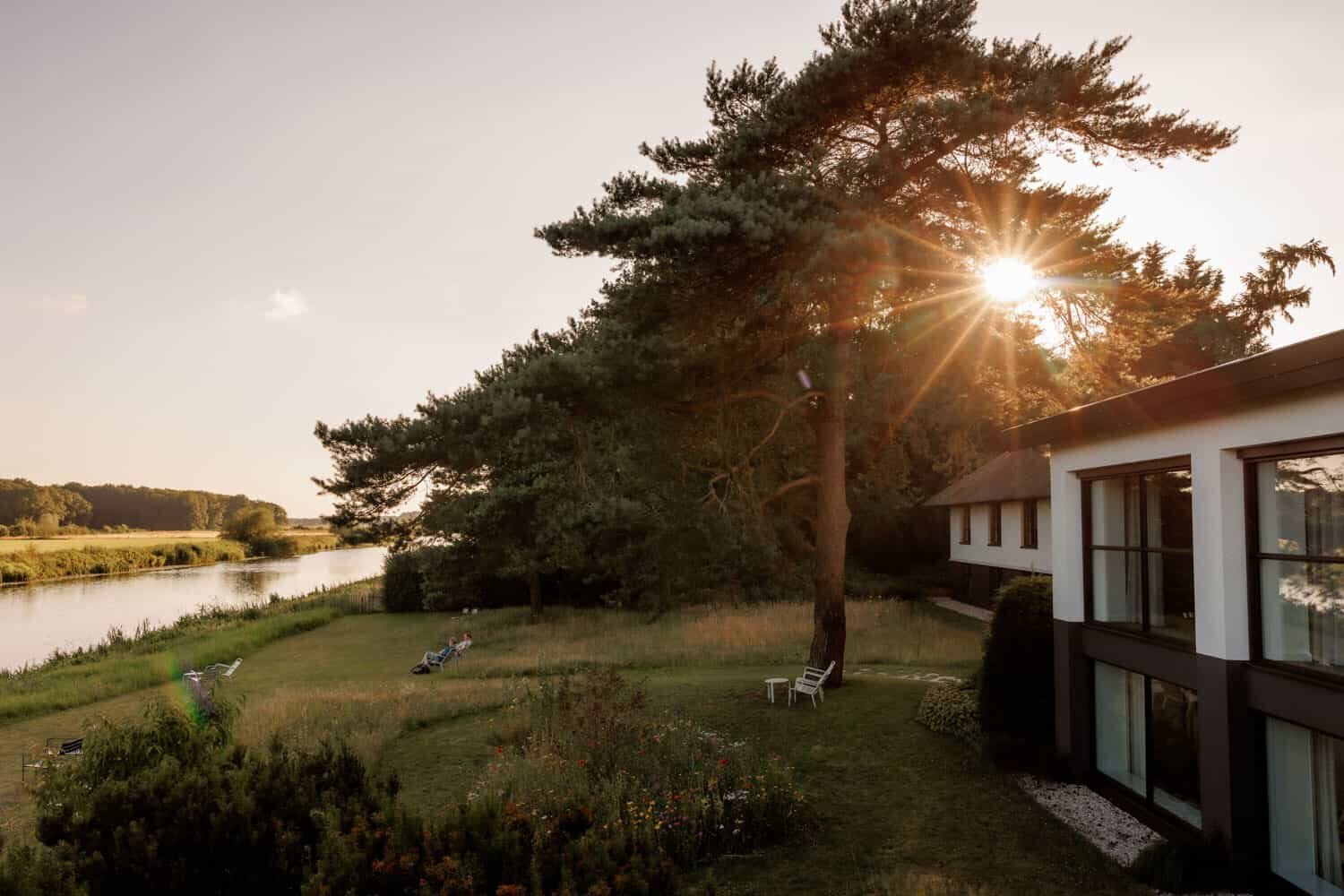 De Vechtzijde van het hotel met de zonneweide aan de rivier.